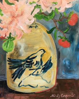 Painted yellow vase with bird design holding pink flowers and autumn leaves on wooden table