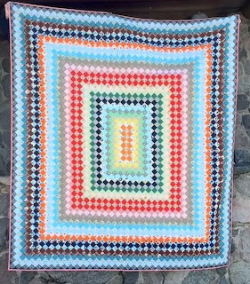 Colorful crocheted granny square blanket with rainbow concentric borders displayed outdoors