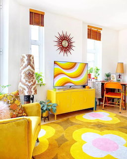 Colorful retro living room with yellow credenza, floral rug, starburst clock, and mid-century decor