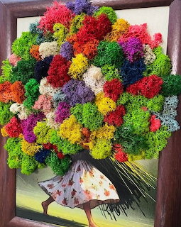 Framed artwork showing a woman partly hidden behind a large colorful flower bouquet