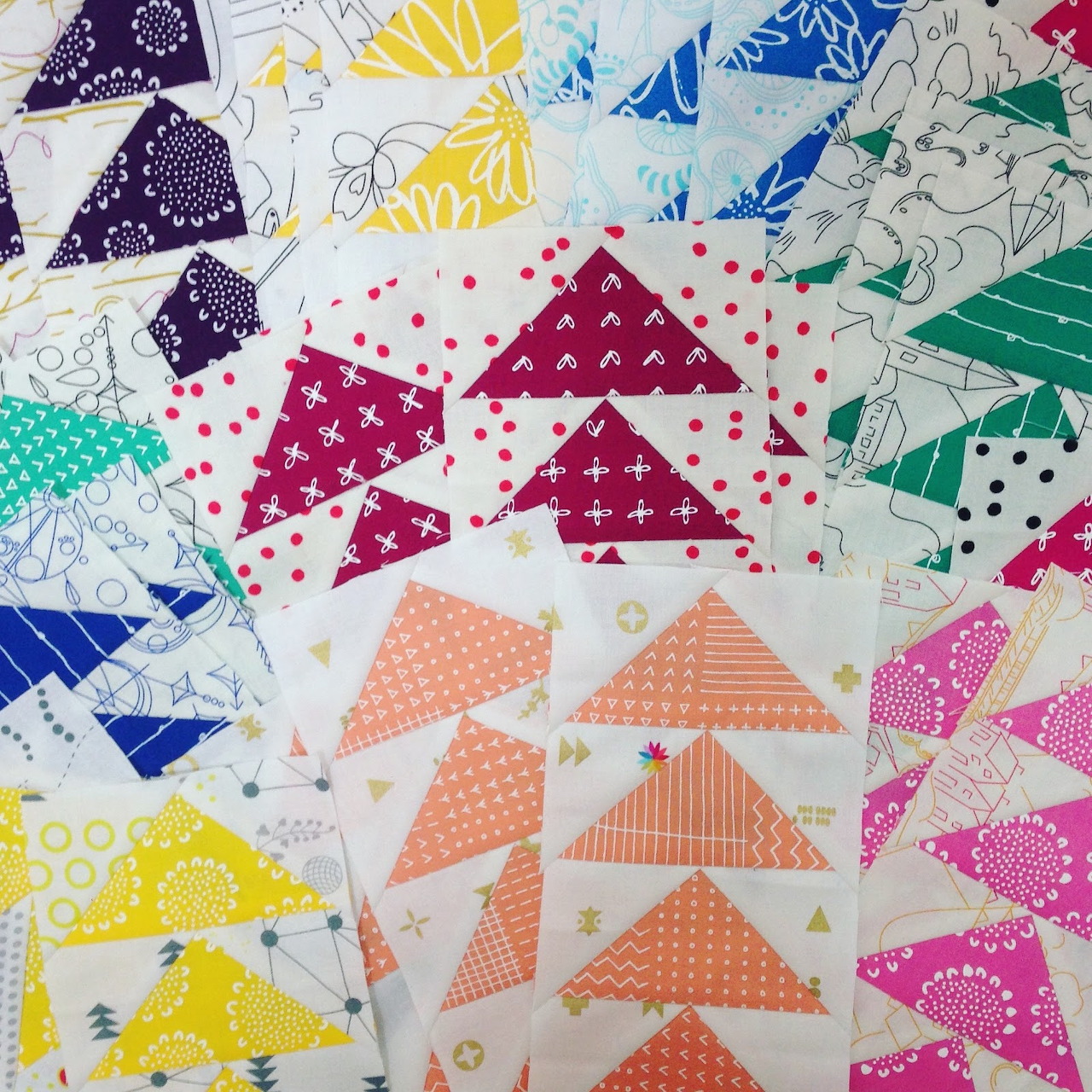 Colorful flying geese quilt blocks in rainbow arrangement with various patterned fabrics
