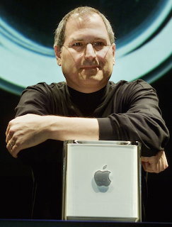 Man in black shirt with crossed arms leaning over a silver computer tower
