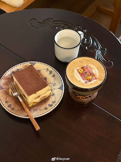 Tiramisu slice on plate with fork beside latte cup and decorative coffee drink on dark table