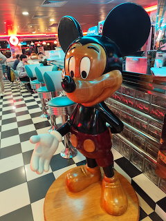 Mickey Mouse statue in a retro diner with black and white checkered floor neon lighting