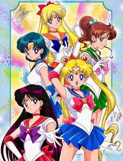Five Sailor Moon characters in colorful uniforms posed together with rainbow background