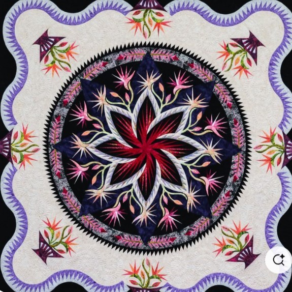 Ornate quilt with red star center, purple border, and floral corner designs