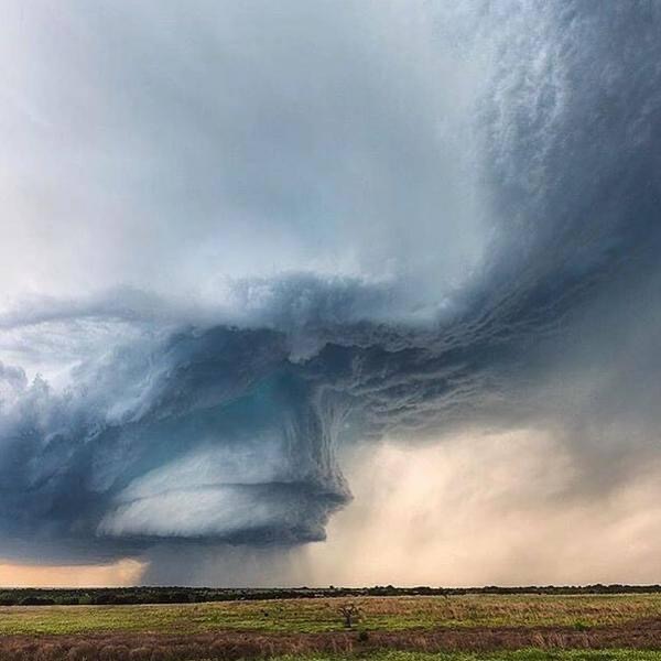 Massive supercell storm cloud over a flat grassy field