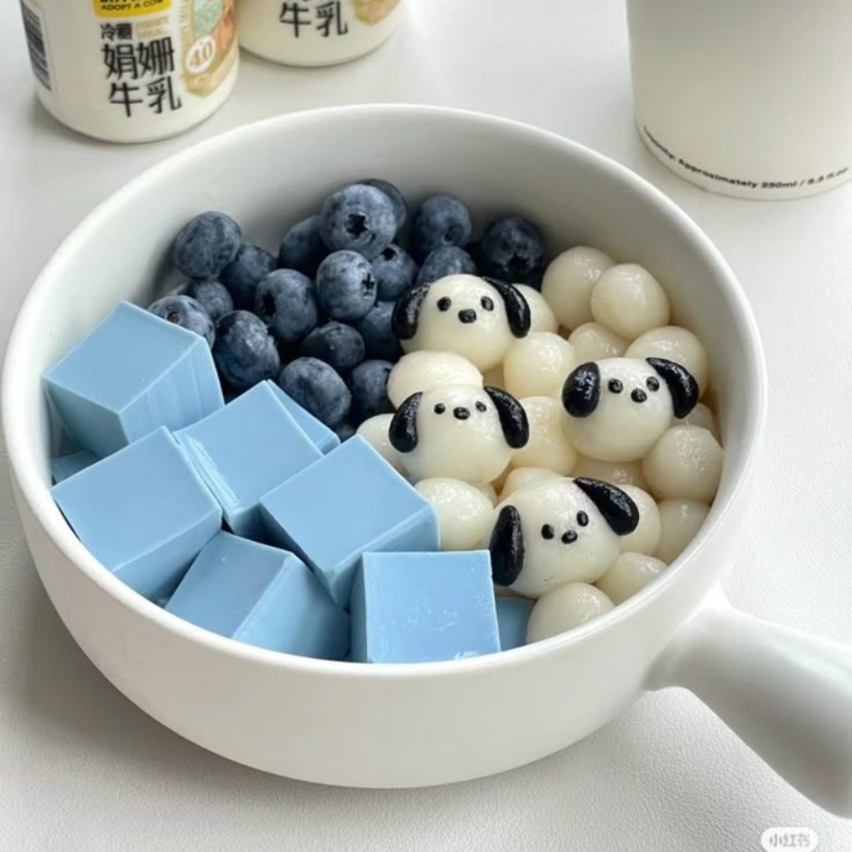Bowl of blue jelly cubes, blueberries, panda mochi and boba pearls on ice