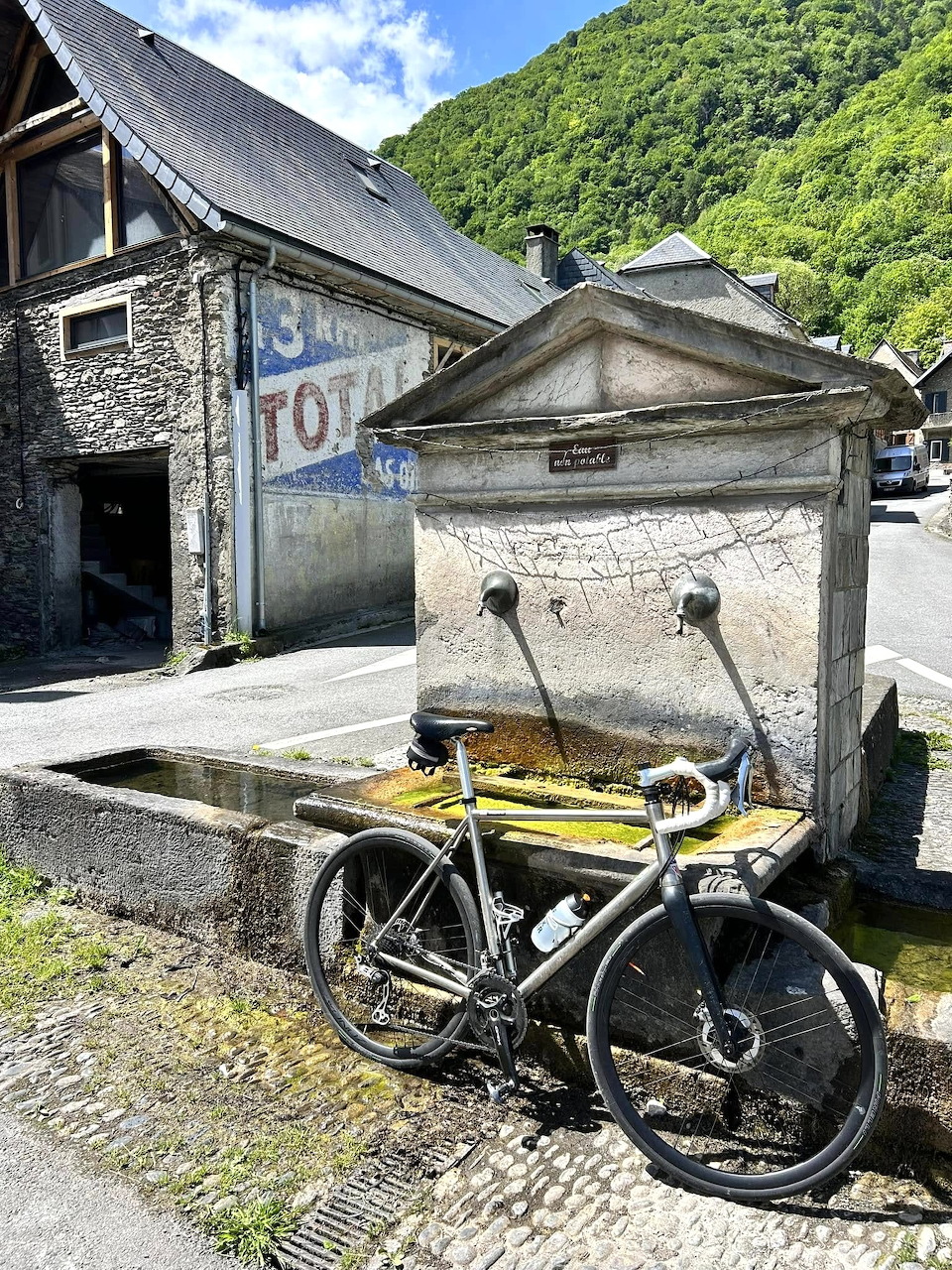 Old bicycle beside a stone fountain in a rustic mountain village street