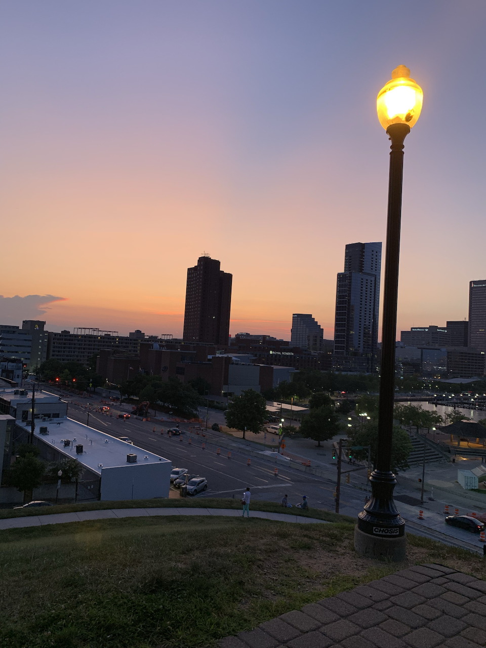 Street lamp at Federal Hill Park with Baltimore skyline silhouetted against a warm sunset sky