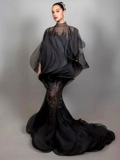 Woman wearing elegant black sheer cape over sequined mermaid gown in studio portrait