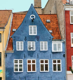 Blue traditional building with white windows and orange tile roof in Copenhagen