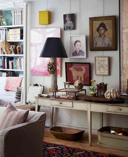 Living room with eclectic gallery wall, vintage furniture, yellow cabinet, striped pillows, and varied artwork