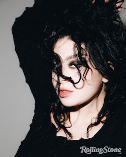Studio portrait of Charli XCX with dark curly hair partly covering her face