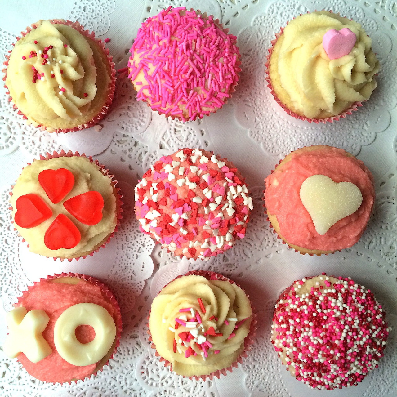 Nine Valentine's Day cupcakes with hearts and pink frosting arranged in rows