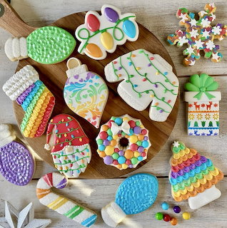 Assorted rainbow-decorated sugar cookies in various shapes on wooden table