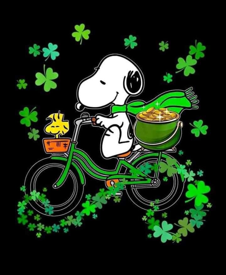Snoopy riding green bike with Woodstock in basket, shamrocks around them on black background