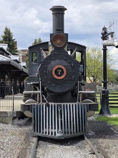 Black vintage steam locomotive number 7 at Greenfield Village with station and trees in background