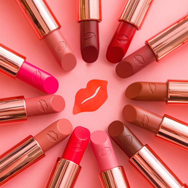 Lipsticks arranged in a circle around a red lip icon on pink background