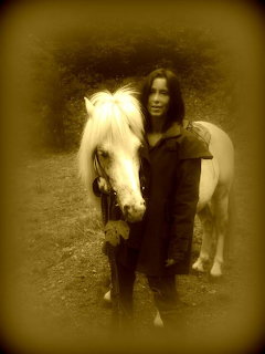Sepia photo of a woman standing next to a white horse outdoors