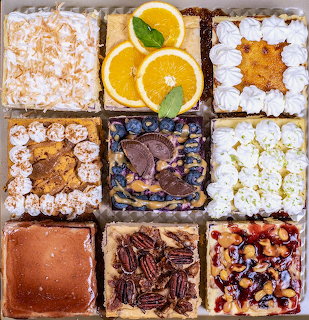 Grid of nine square dessert tarts with various toppings including coconut, orange slices, chocolate, pecans, and berries