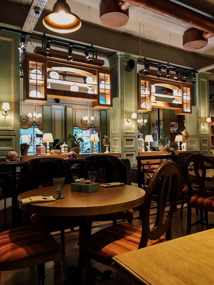 Warm coffee house interior with wooden furniture, green walls, pendant lights, and vintage service counter