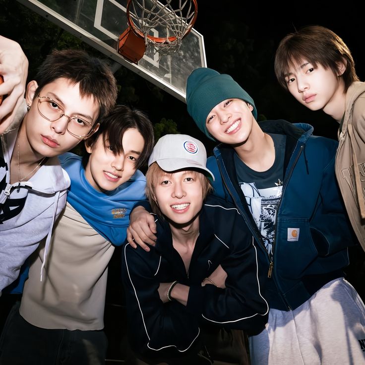 Five young men in casual clothing smiling and posing closely together for a group portrait