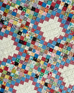 Colorful patchwork quilt with small fabric squares and cream diamond patterns