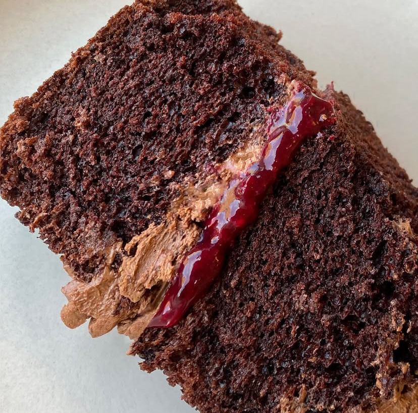 Close-up of a chocolate cake slice with cream filling and glossy jam