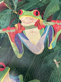 Colorful quilt showing red-eyed tree frogs on green leaves with a dragonfly