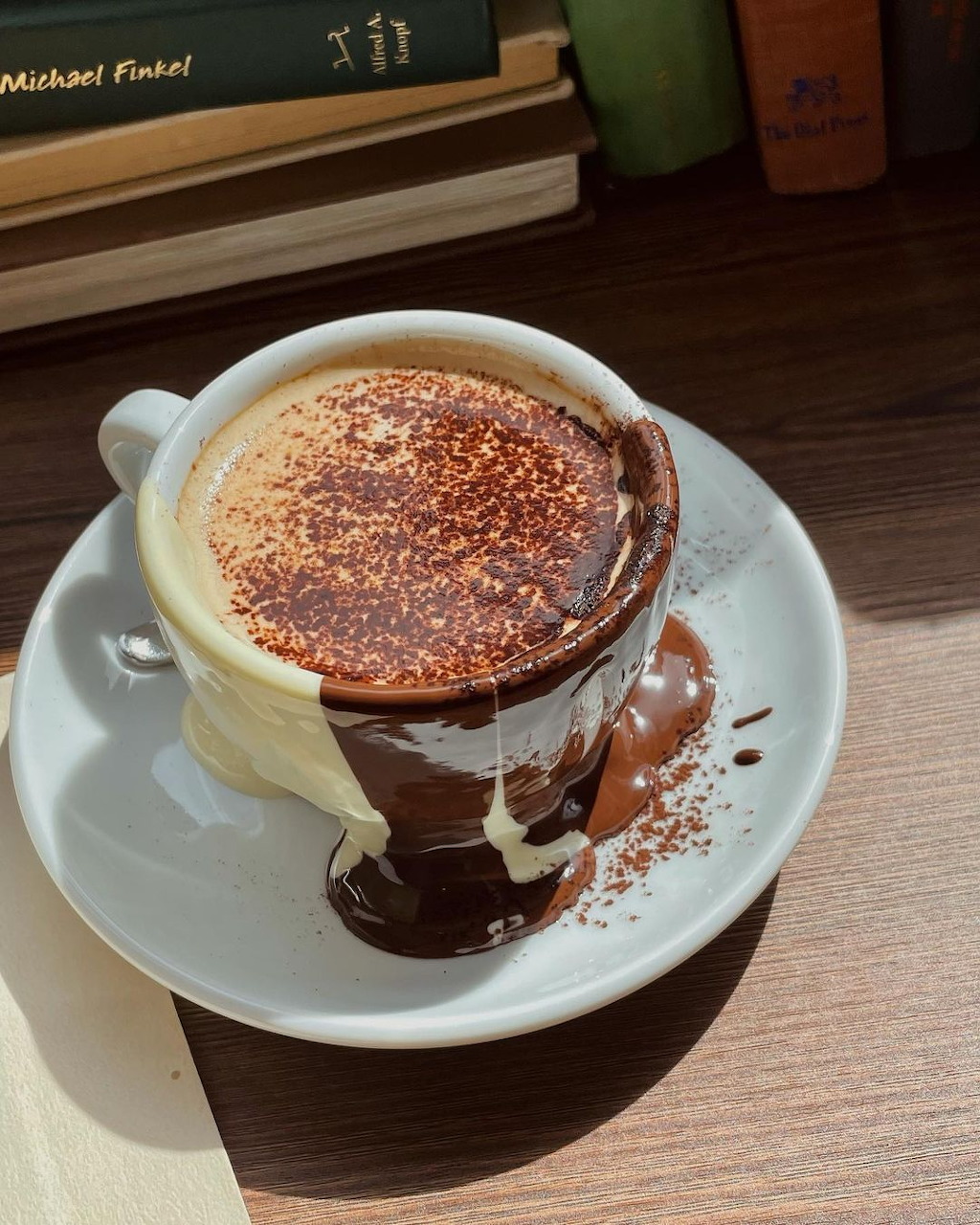 Mocha latte with chocolate drizzle and cocoa powder in white cup on wooden table