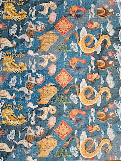Blue ornamental pattern with golden dragons, birds, clouds, and repeating decorative motifs