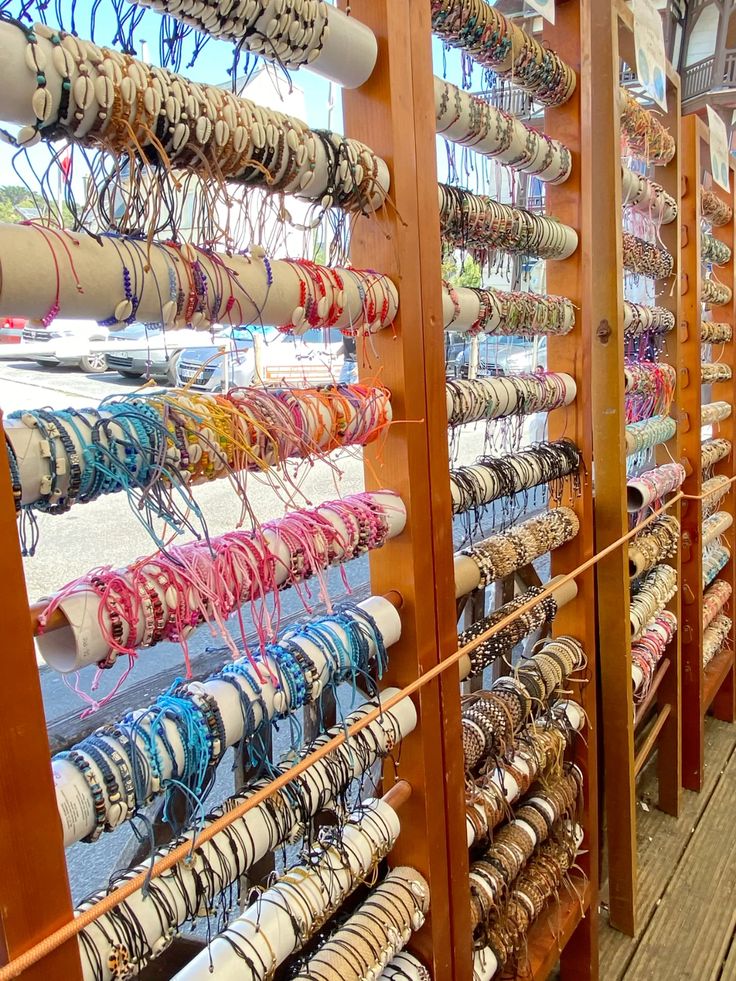 Wooden display racks filled with rows of colorful beaded and woven bracelets at a beach shop
