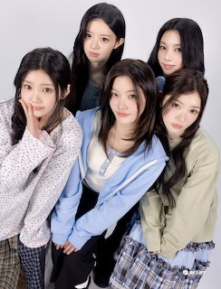 Five young Asian women posing together in casual clothing against a grey studio background
