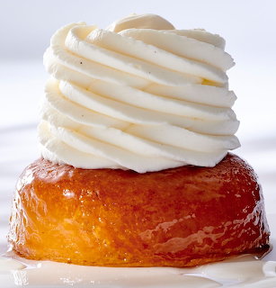 Baba au rhum with glossy caramelized cake base and tall spiral of white cream on top