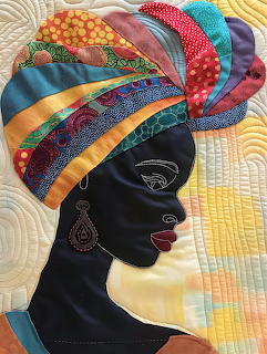 Quilted fabric art of an African woman's profile with colorful head wrap and decorative earring