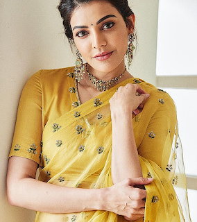 Woman in yellow embroidered saree with silver jewelry posing against a light background