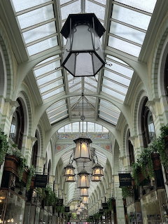 Victorian glass-roofed arcade with hanging lanterns and ornate arched architecture in Norwich