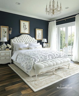 Elegant bedroom with tufted white bed, bench, dark walls, framed art, and tall windows
