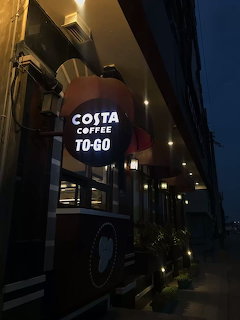 Illuminated coffee shop sign outside a building at night