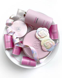 Pink beauty bottles, jars, and floral soaps with shiny ribbons on a white plate