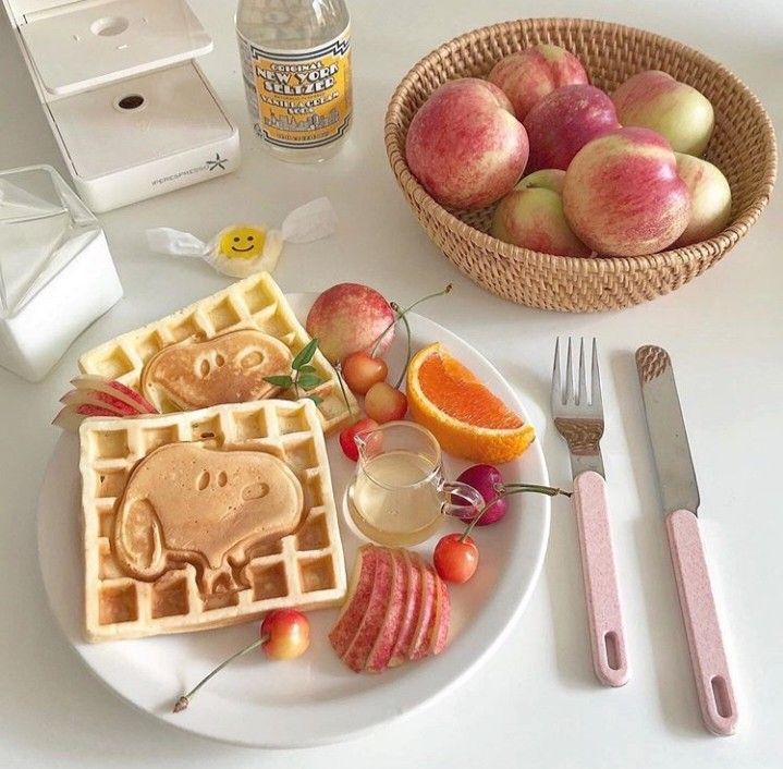 Breakfast table with bear-shaped waffles, peaches in basket, orange slices, and strawberries on white plate