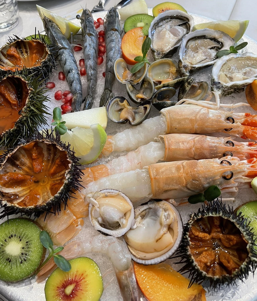 Raw seafood platter with prawns, oysters, scallops, sea urchins and lemon slices on ice