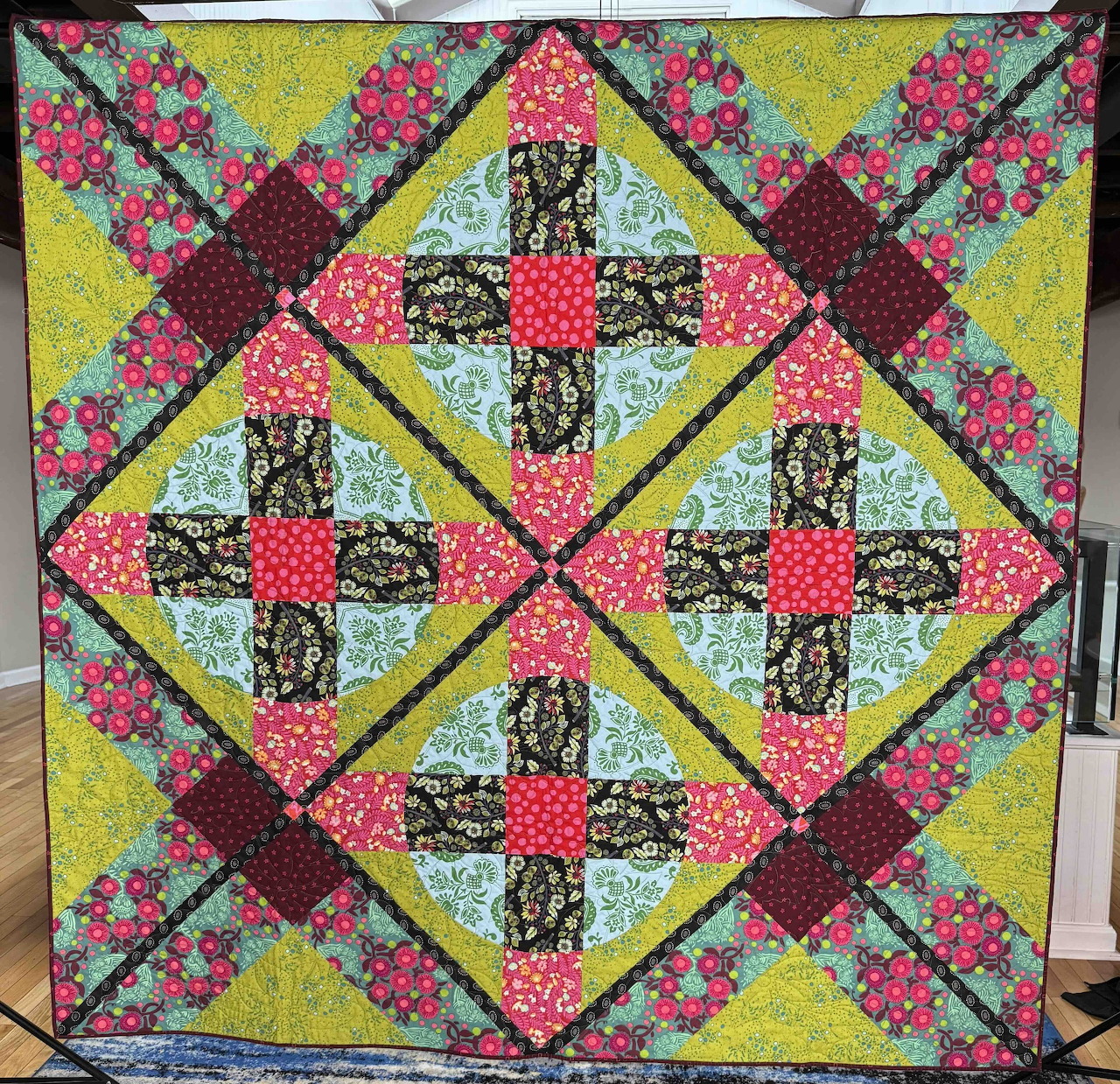 Handmade quilt with floral patchwork crosses and diamonds in pink, yellow, and turquoise fabrics