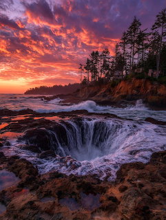 Waves pouring into Thor's Well sinkhole on Oregon coast at sunset with dramatic orange and purple clouds