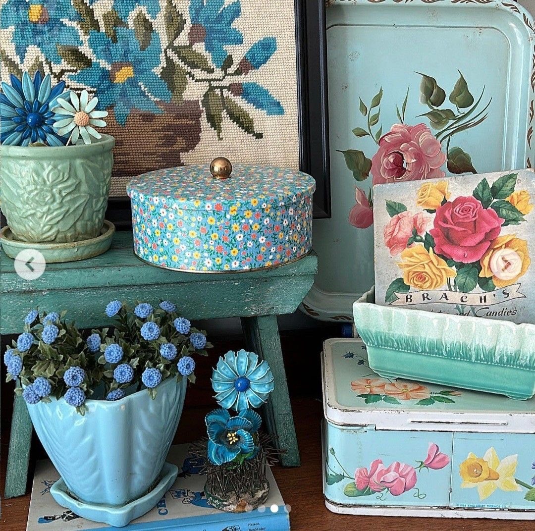 Collection of turquoise and floral vintage tins with embroidered flowers arranged on rustic wooden shelves