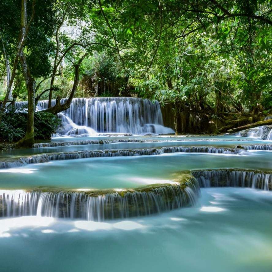 Tiered turquoise pools and waterfalls in a lush green forest