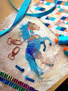Handmade crossbody bag with embroidered blue horse design and colorful geometric pattern fabric