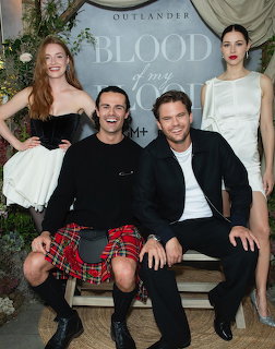 Four actors posing together in front of an Outlander: Blood of My Blood backdrop indoors.