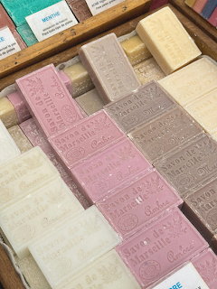 Close-up of assorted pastel soap bars arranged in a wooden tray